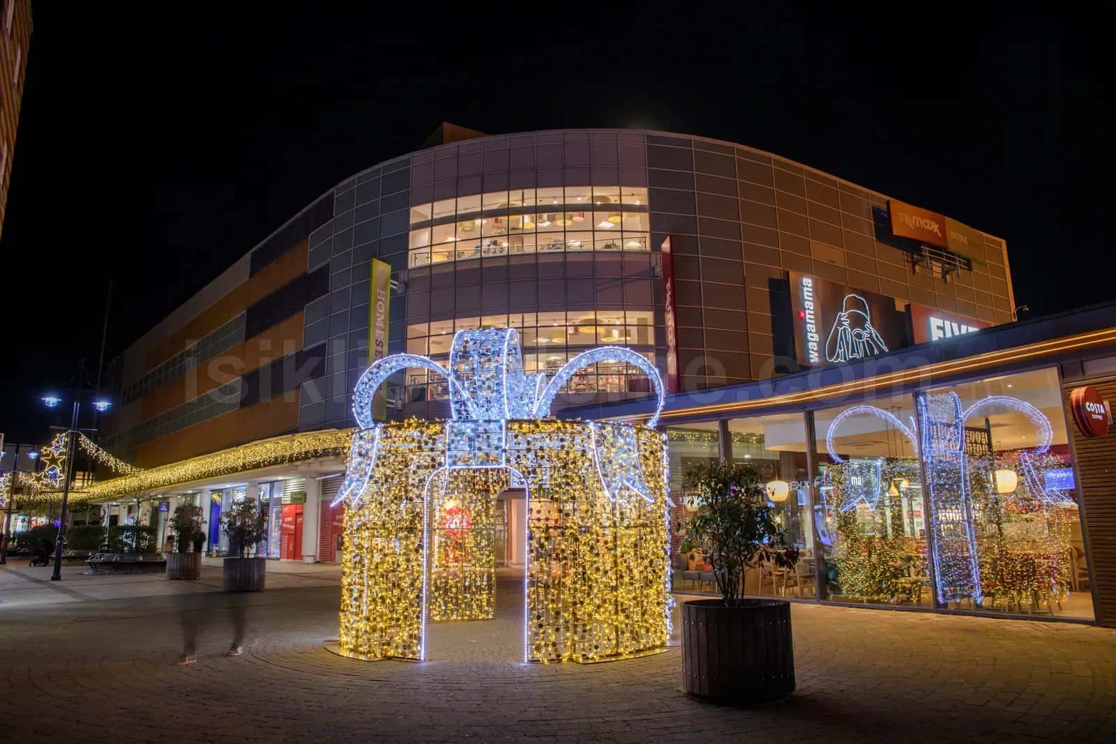 Cok katli AVM binasi onunde altin ve mavi led isikli buyuk hediye kutusu figuru gece cekim