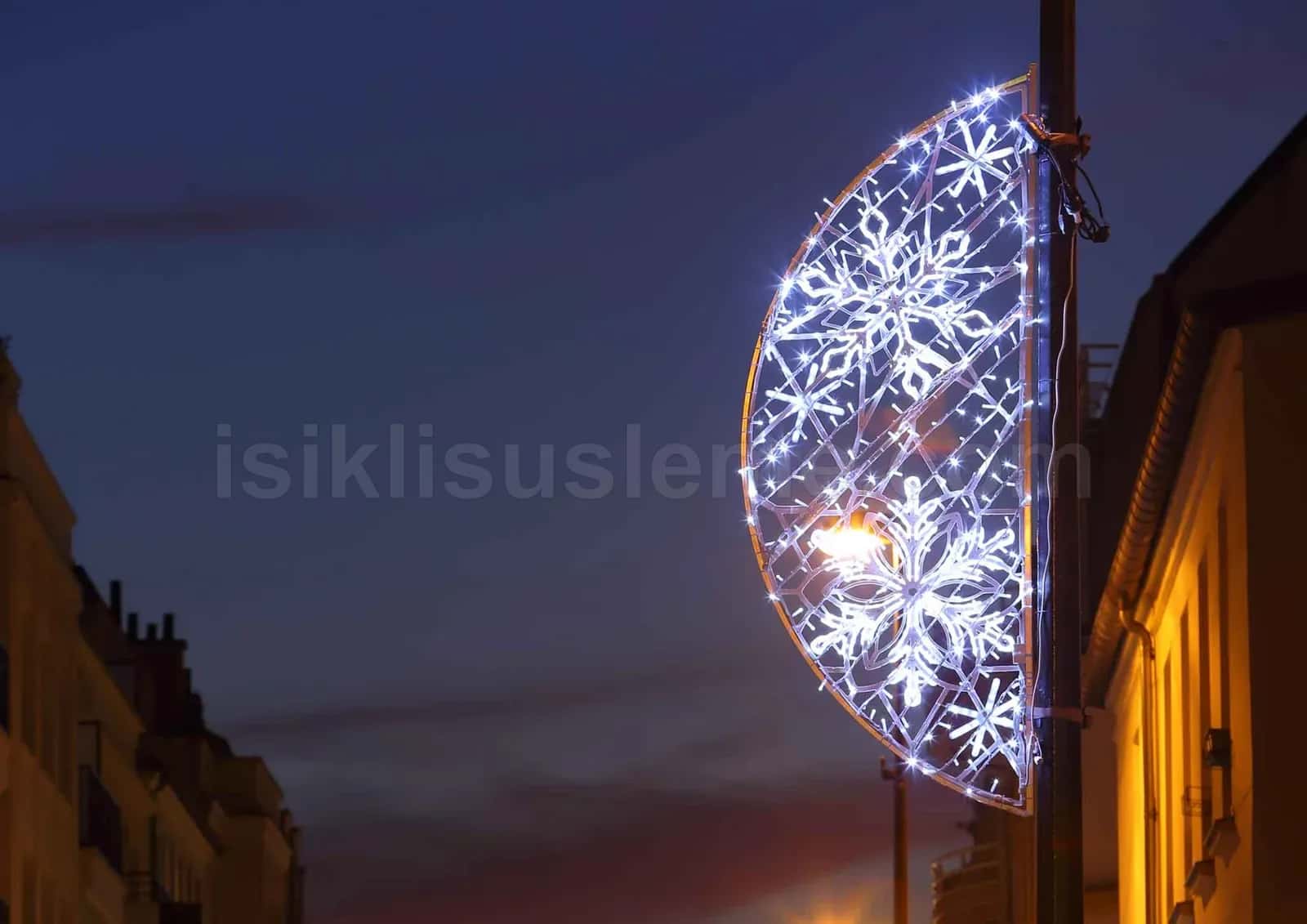 Alacakaranlikta bir elektrik diregi uzerine monte edilmis beyaz LED kar tanesi motifi