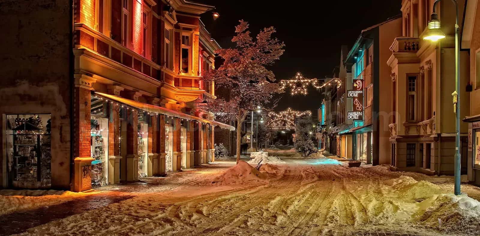 Karla kapli tarihi bir cadde uzerinde yilbasi LED isiklari ve kar tanesi motifleri gece gorunu
