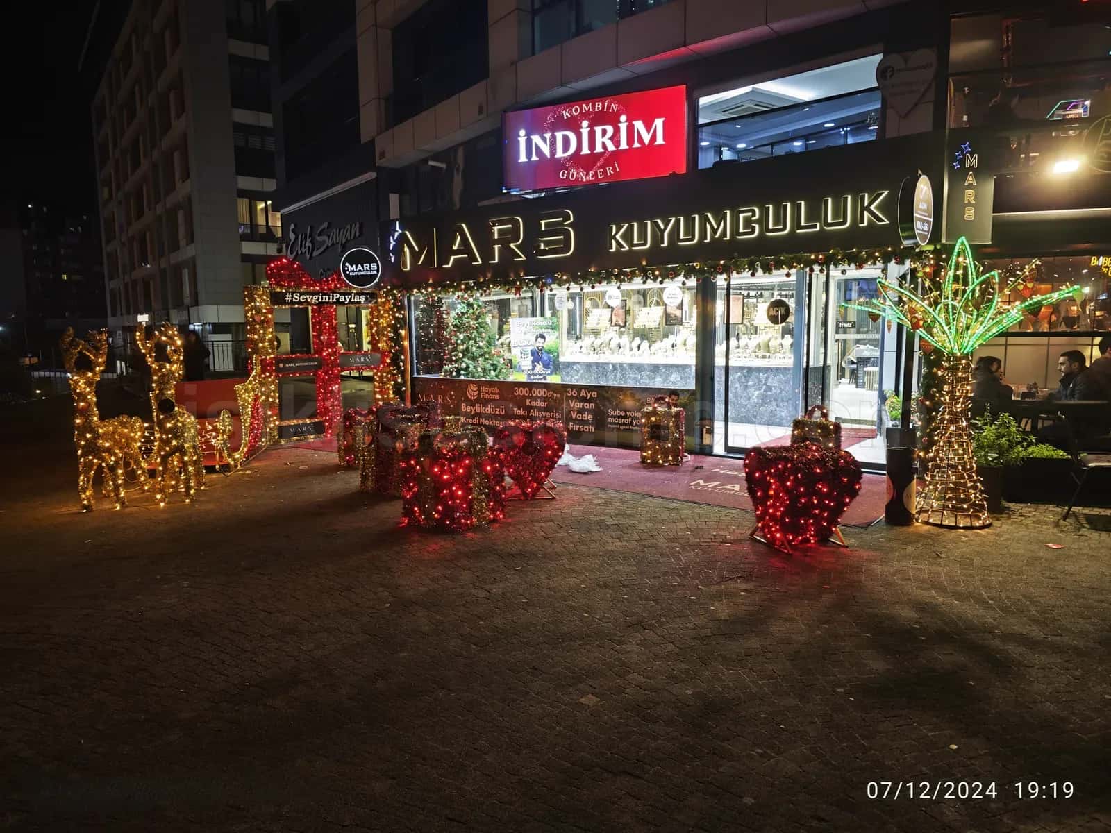 Kuyumcu magazasi onunde kirmizi ledli ren geyigi ve kalp figurlerinden olusan yilbasi sahnesi