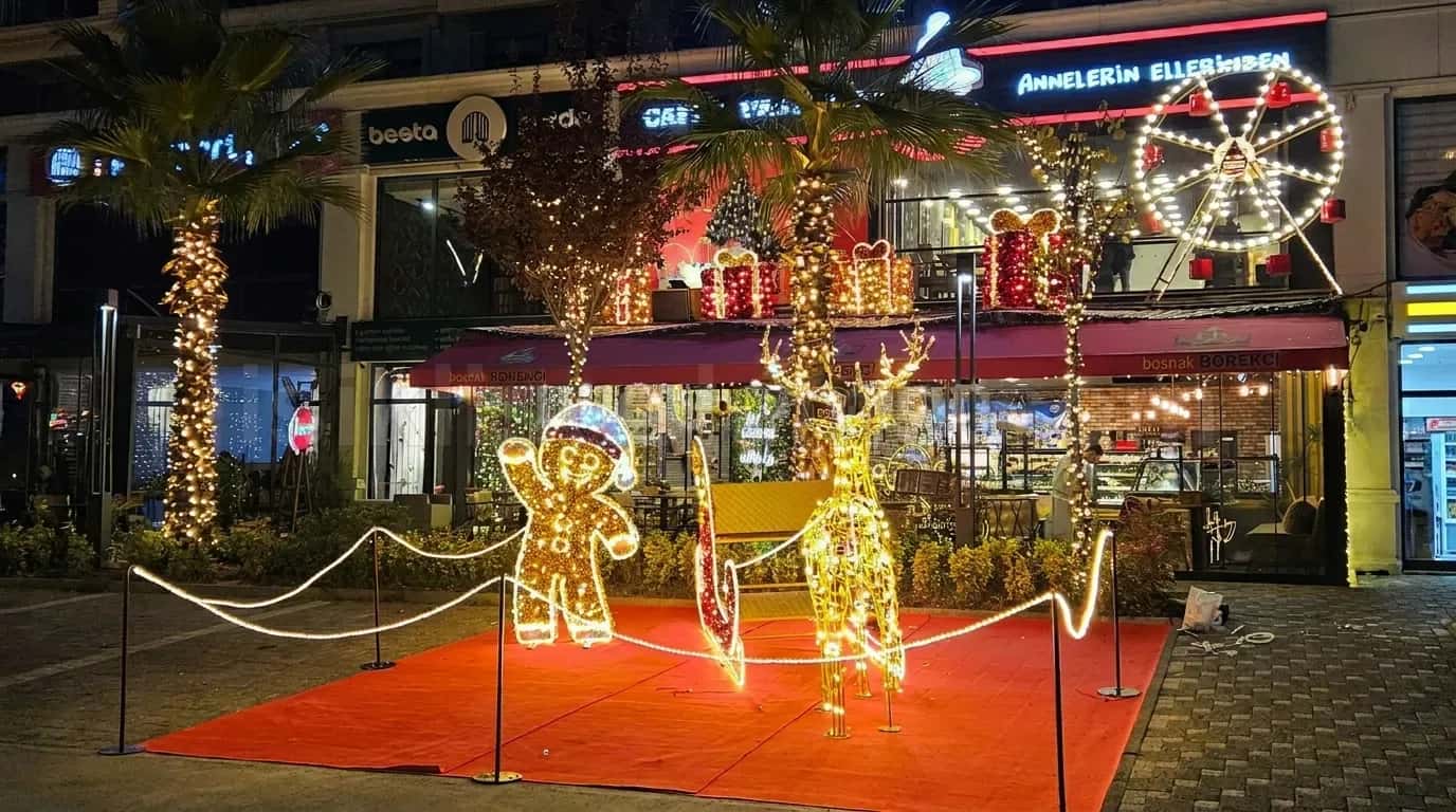 Kafe onunde kirmizi hali uzerinde altin rengi LED gingerbread adam geyik ve kizak figuru