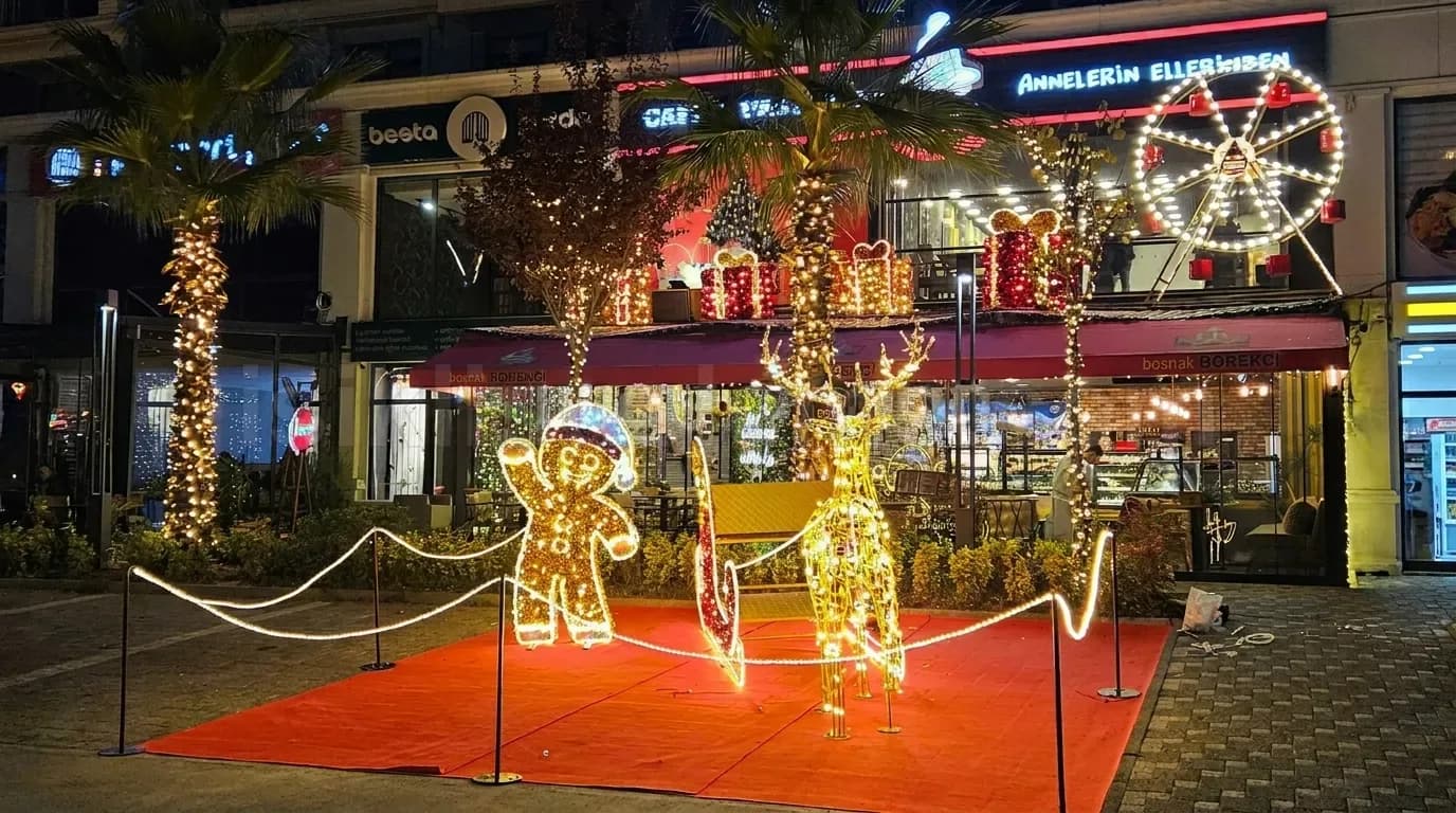 Kafe onunde kirmizi hali uzerinde altin rengi LED gingerbread adam geyik ve kizak figuru