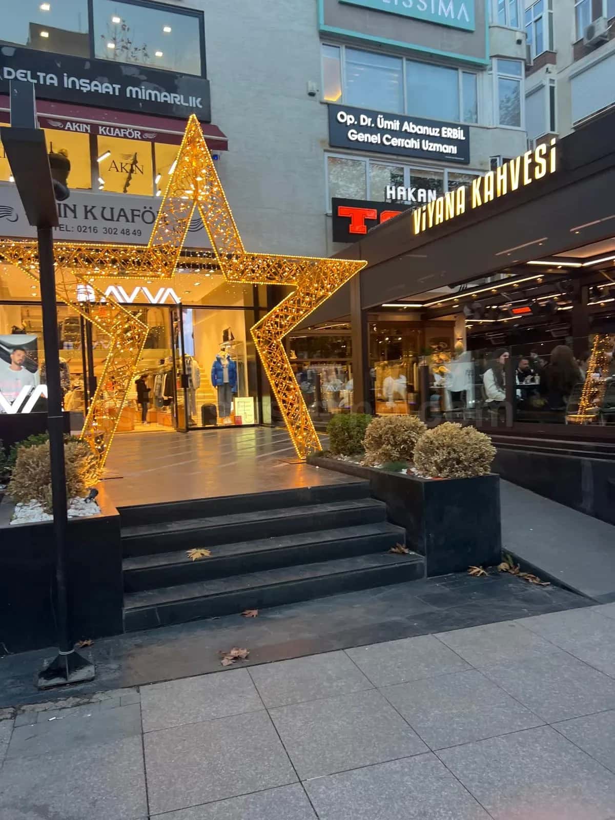 Magaza girisinde merdivenler onune yerlestirilmis buyuk altin sari LED yildiz figuru