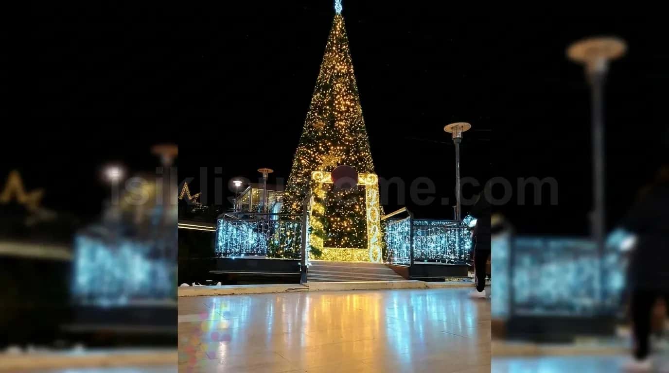Gece acik alanda altin led isikli dev yilbasi cam agaci ve isikli kapi kemeri