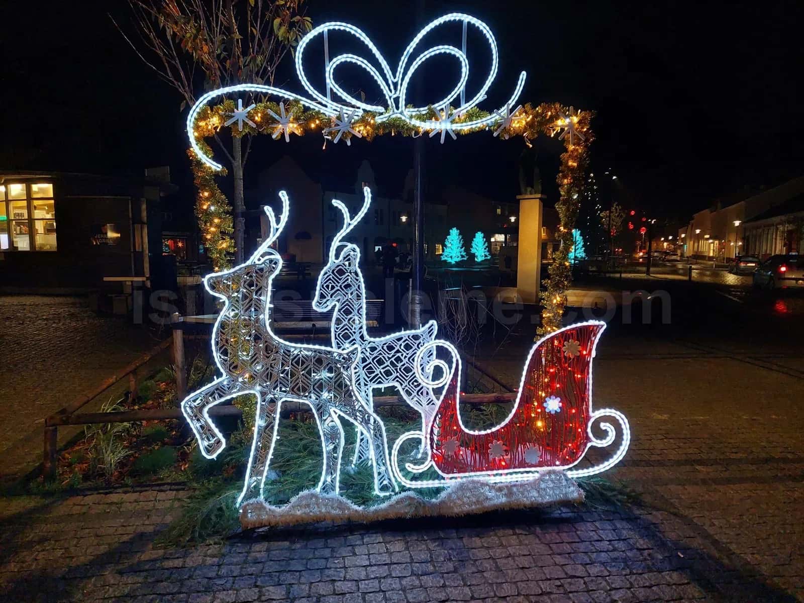 Gece meydan kaldirimi uzerinde beyaz ve kirmizi LED isikli buyuk geyik kizak figur