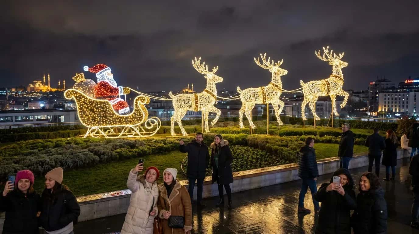 Gece sehir siluetiyle noel baba kizagi ve altin rengi geyik LED figurlerinin onunde poz veren ziyaretciler