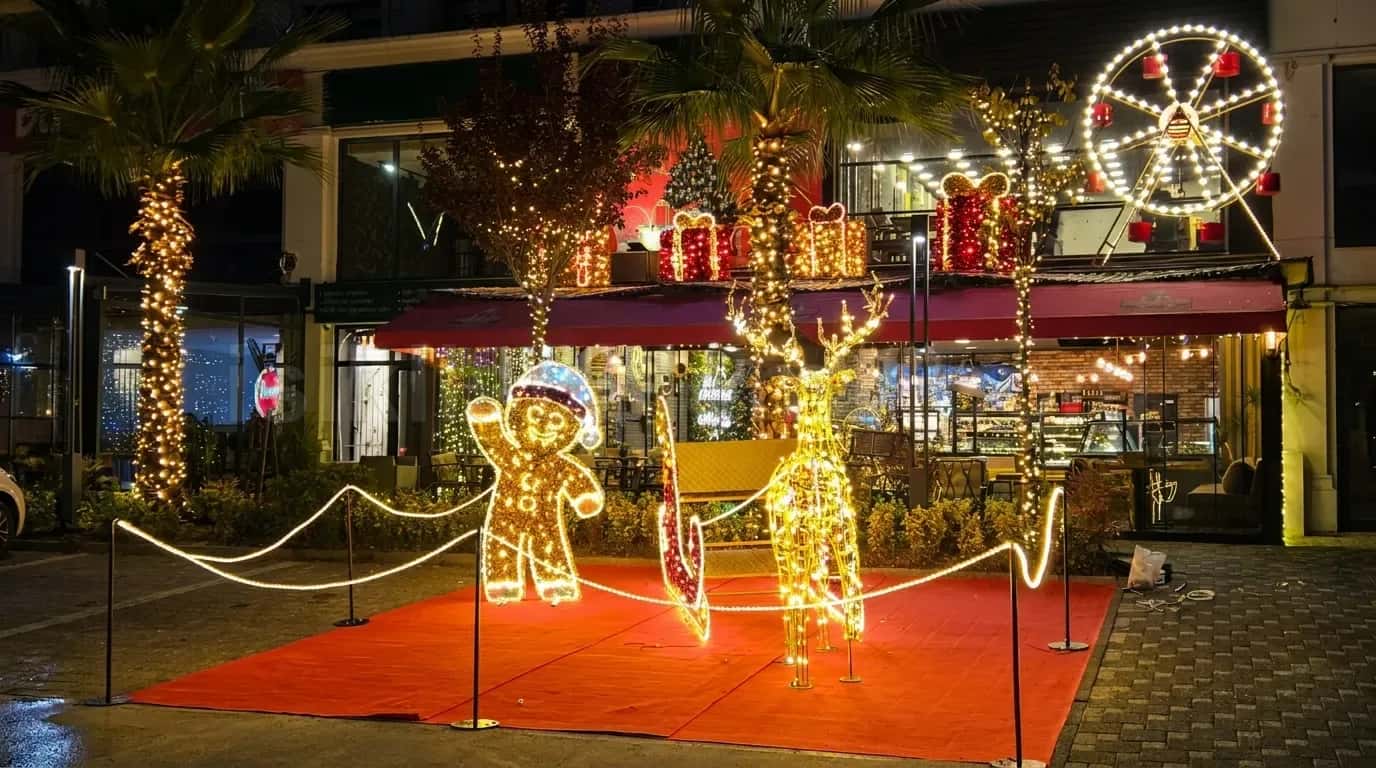 Palmiye agaclari ve dukkan onunde altin LED geyik kizak ve gingerbread adam figuru gece