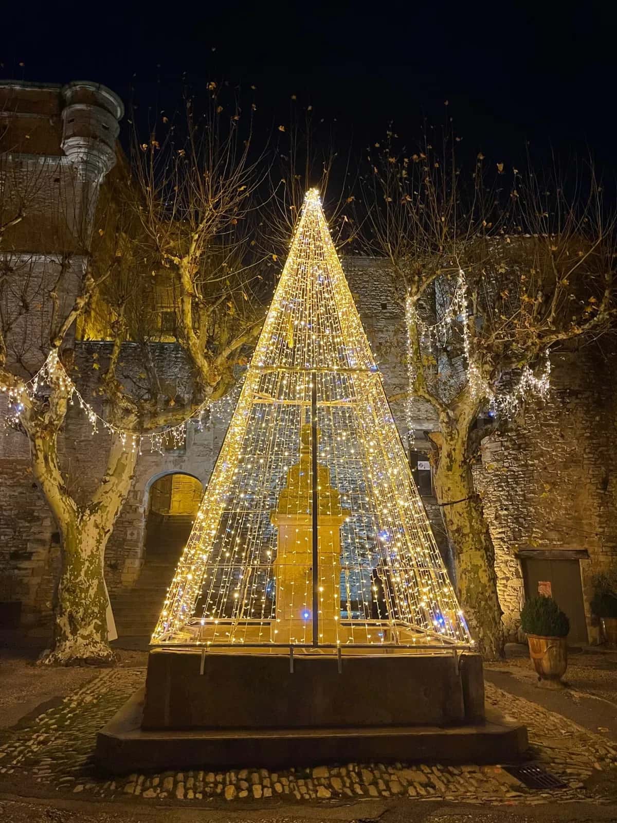 Tas duvarlarin onunde sari sicak beyaz LED piramit yilbasi agaci gece fotografı