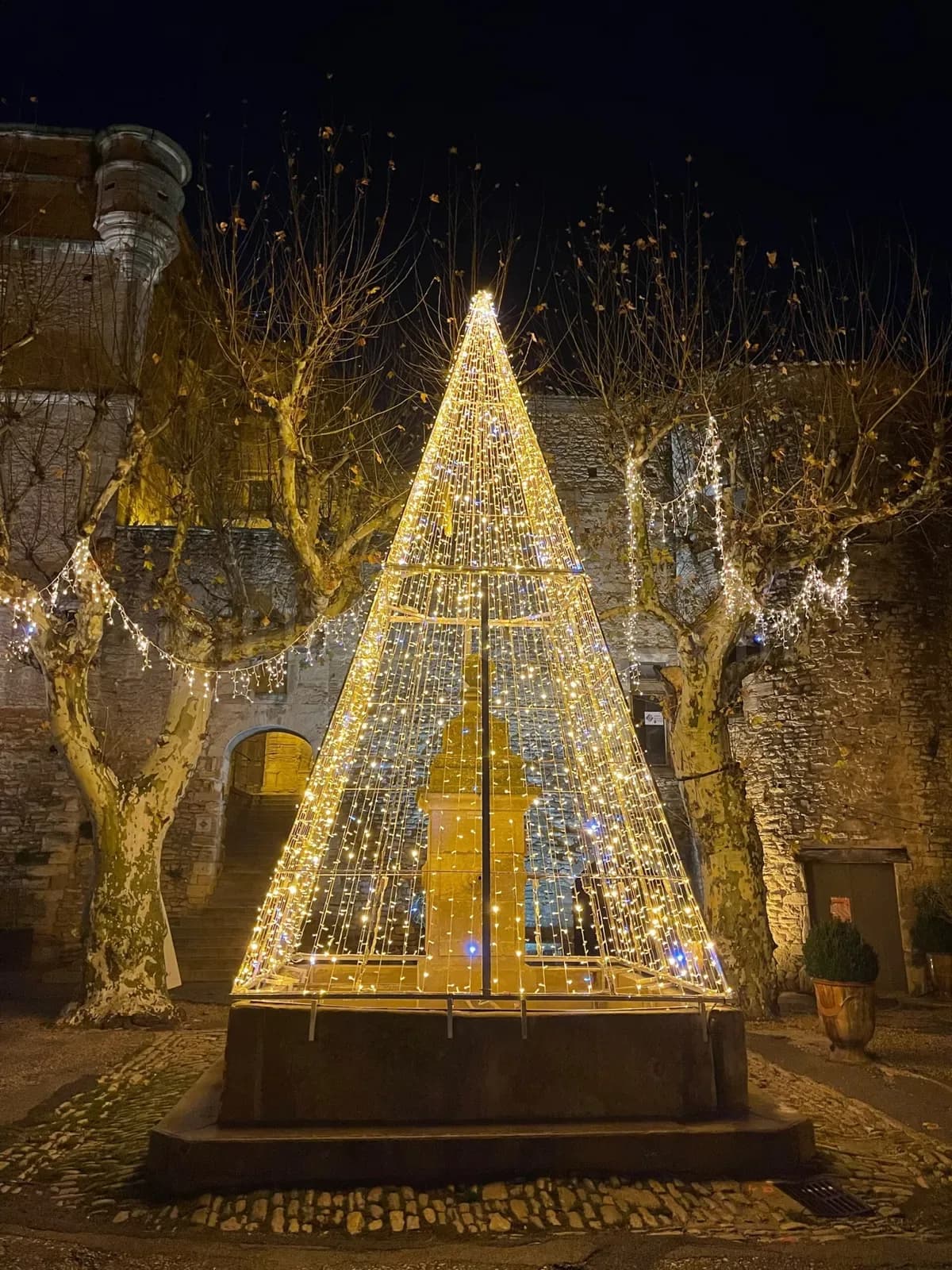 Tas duvarlarin onunde sari sicak beyaz LED piramit yilbasi agaci gece fotografı