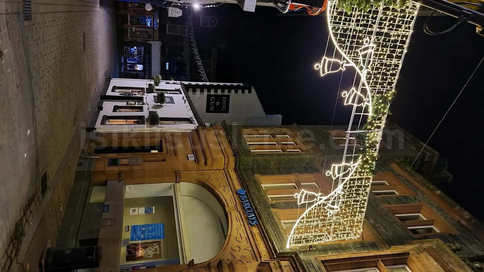 Tarihi tas binalar arasindan asilan beyaz LED zil ve yildiz motifleri ile yilbasi cadde susleme gece gorunumu
