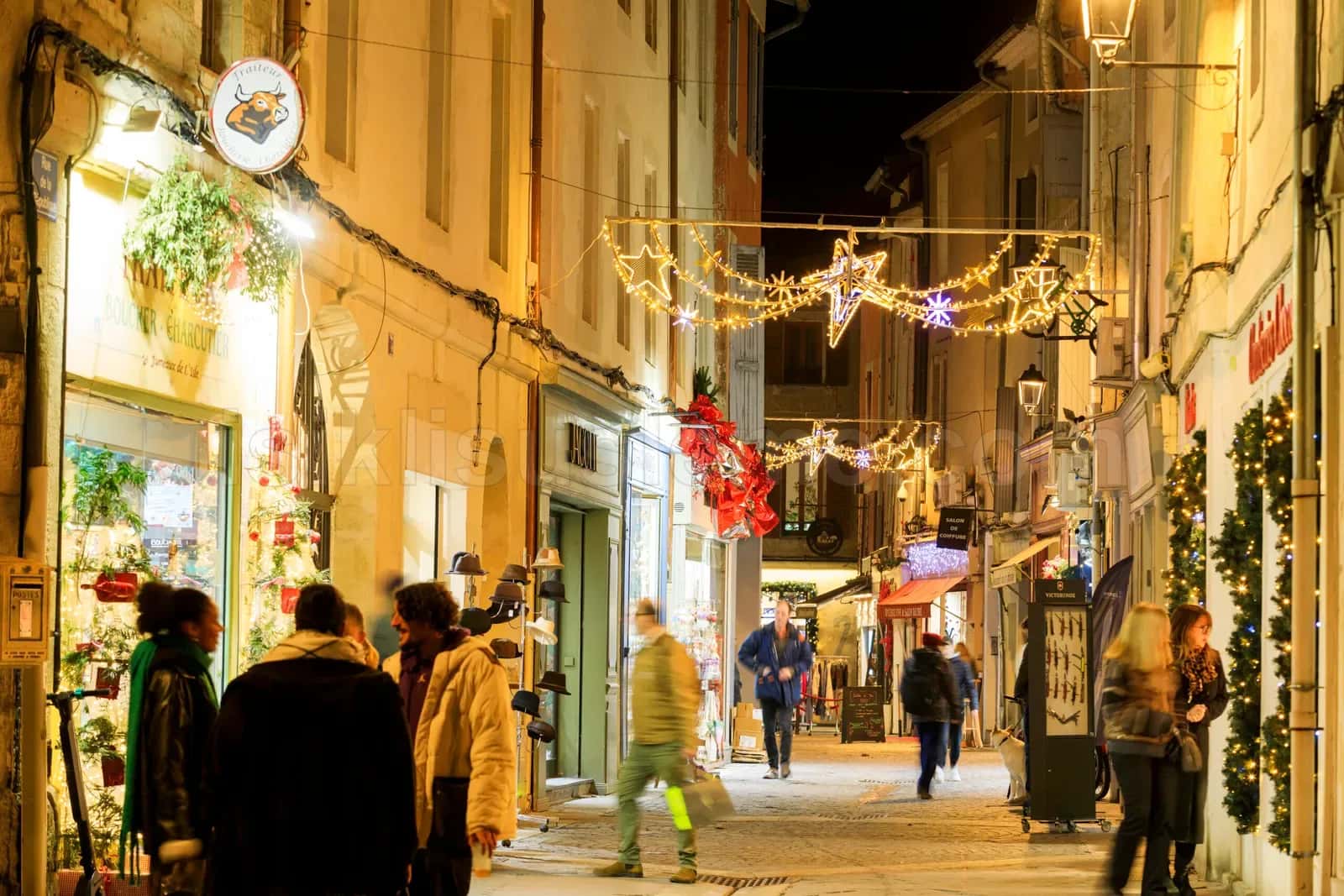 Gece yuruyen insanlarla dolu dar tarihi sokakta yildiz motifli LED susleme catallari