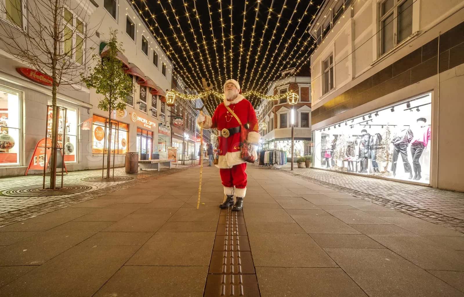 Yaya alisveris caddesinde tavan boyunca geren sari LED perde altinda Noel Baba kostumlu kisi