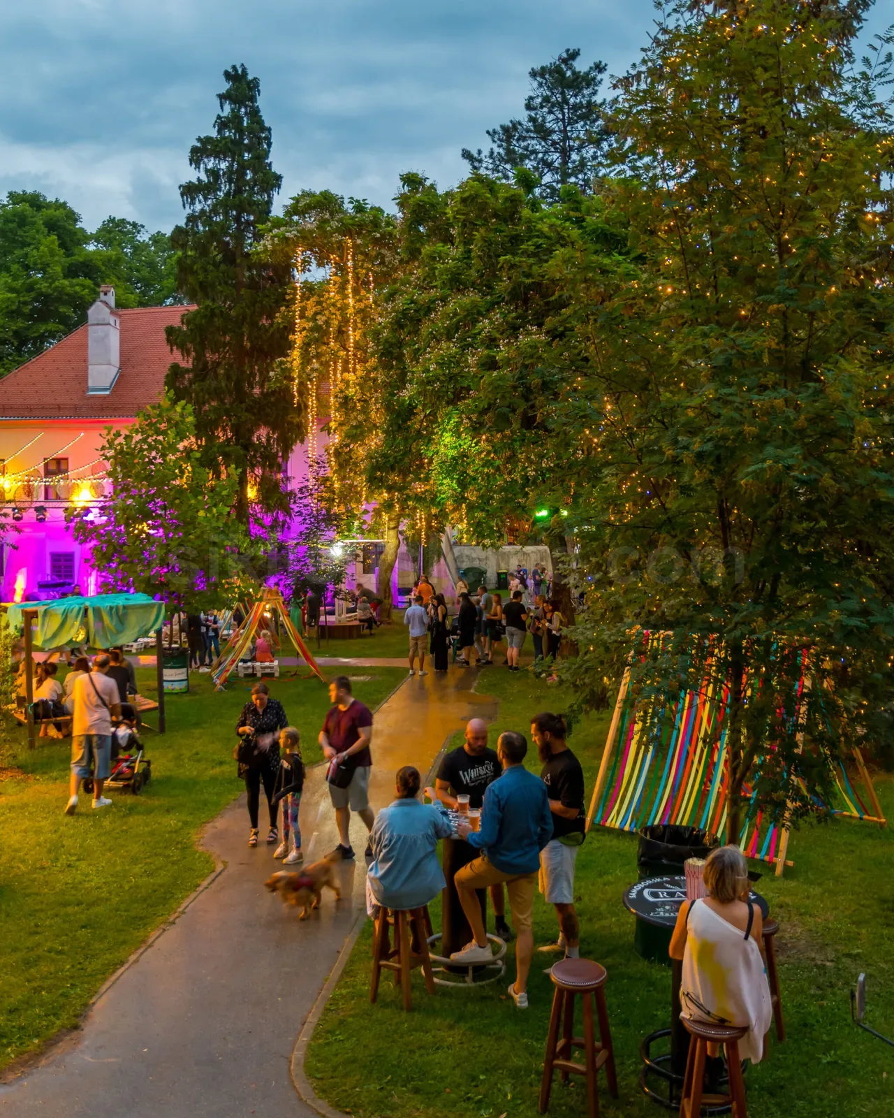 Agaclarin ve binaların LED susleme ile donandigi acik hava kafe veya festival bahce alani aksam goruntüsu