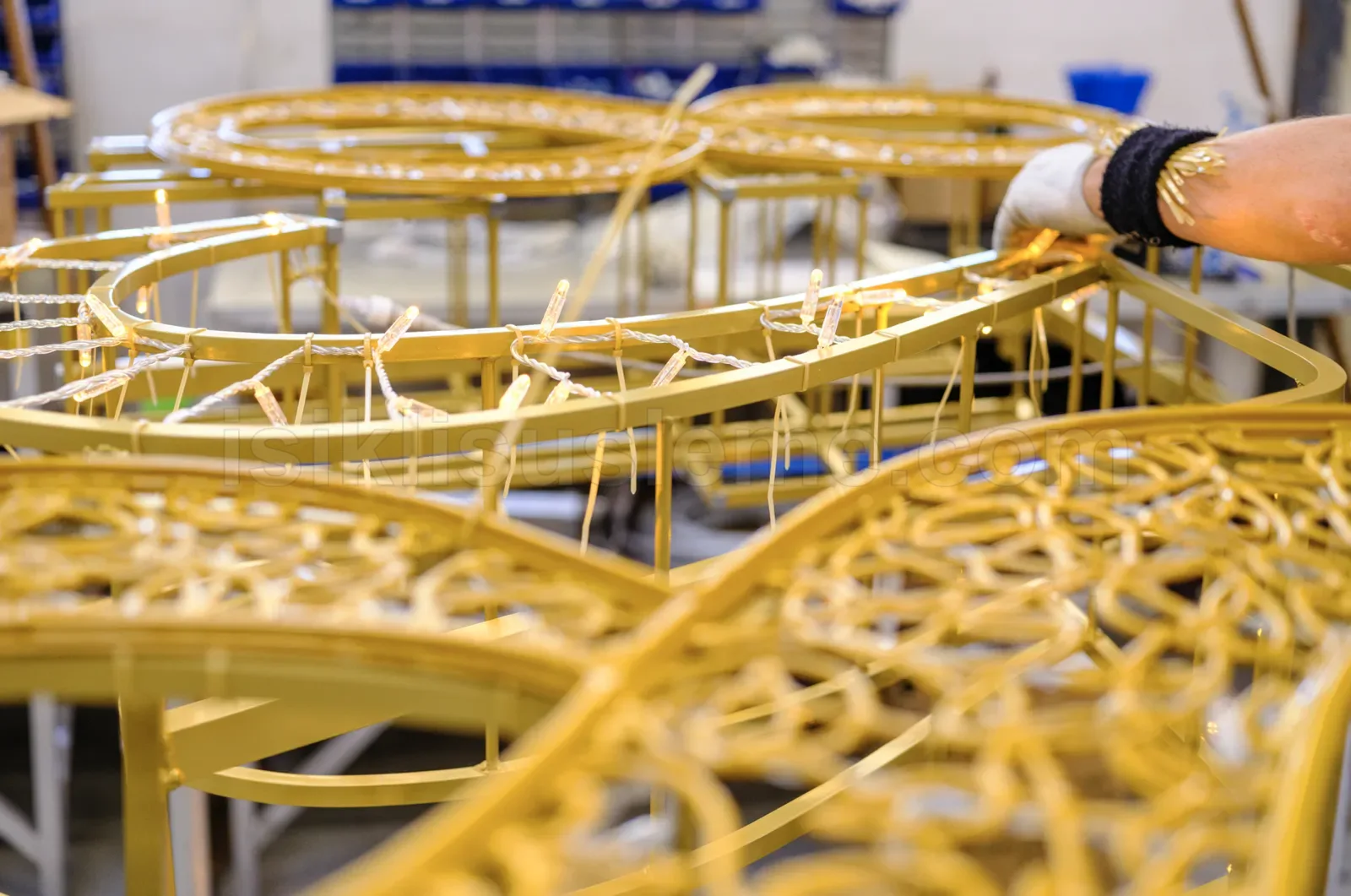 Üretim atölyesinde işçi altın boyalı metal LED süsleme çerçevesini monte ediyor