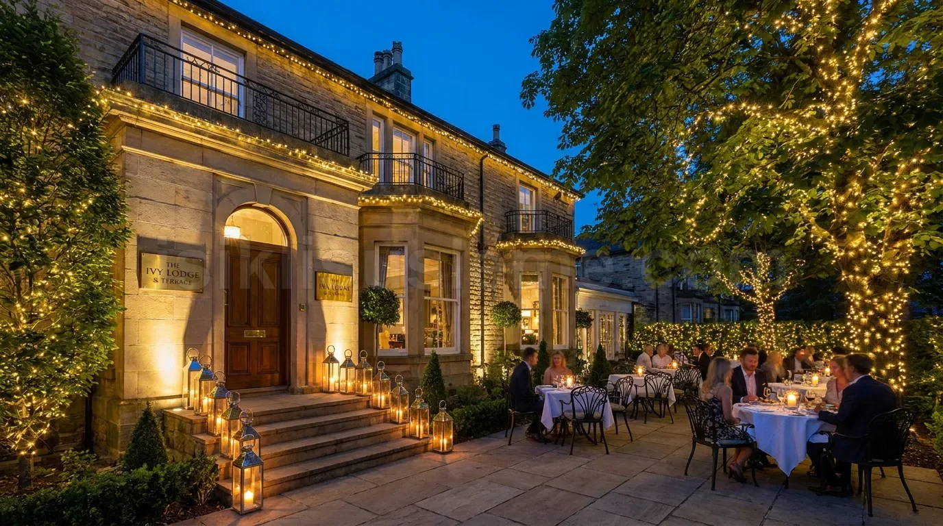 Gece vakti musteri dolu bahce restoraninda agaclara ve girisa sarili sicak beyaz LED susleme