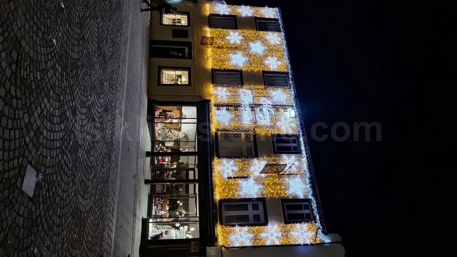Cok katli ticari bina dis cephesi altin ve beyaz kar tanesi LED motif susleme ile gece gorunumu