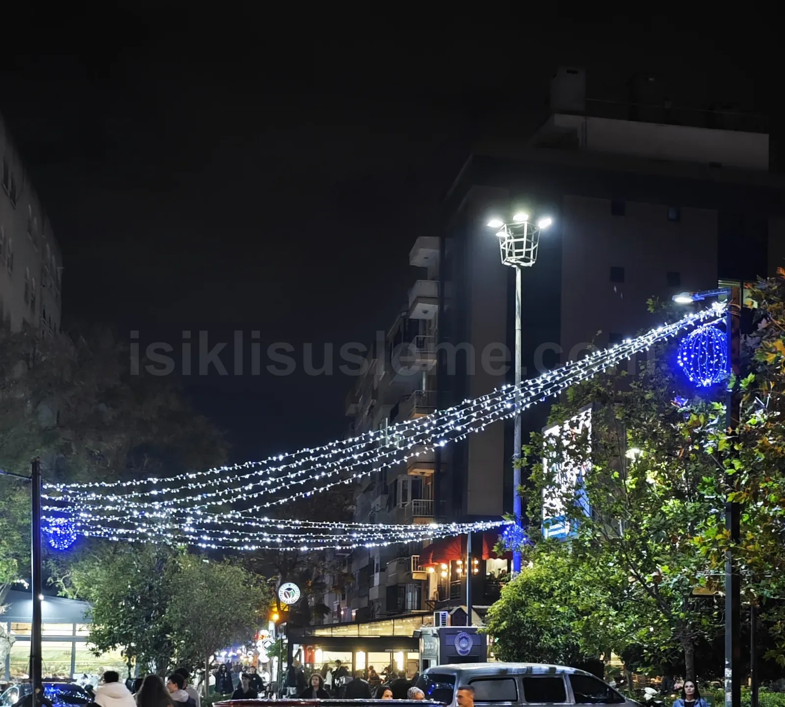 Gece sehir bulvarinda direkler arasina gerilmis mavi beyaz LED zincir susleme ve mavi LED top dekorasyonu