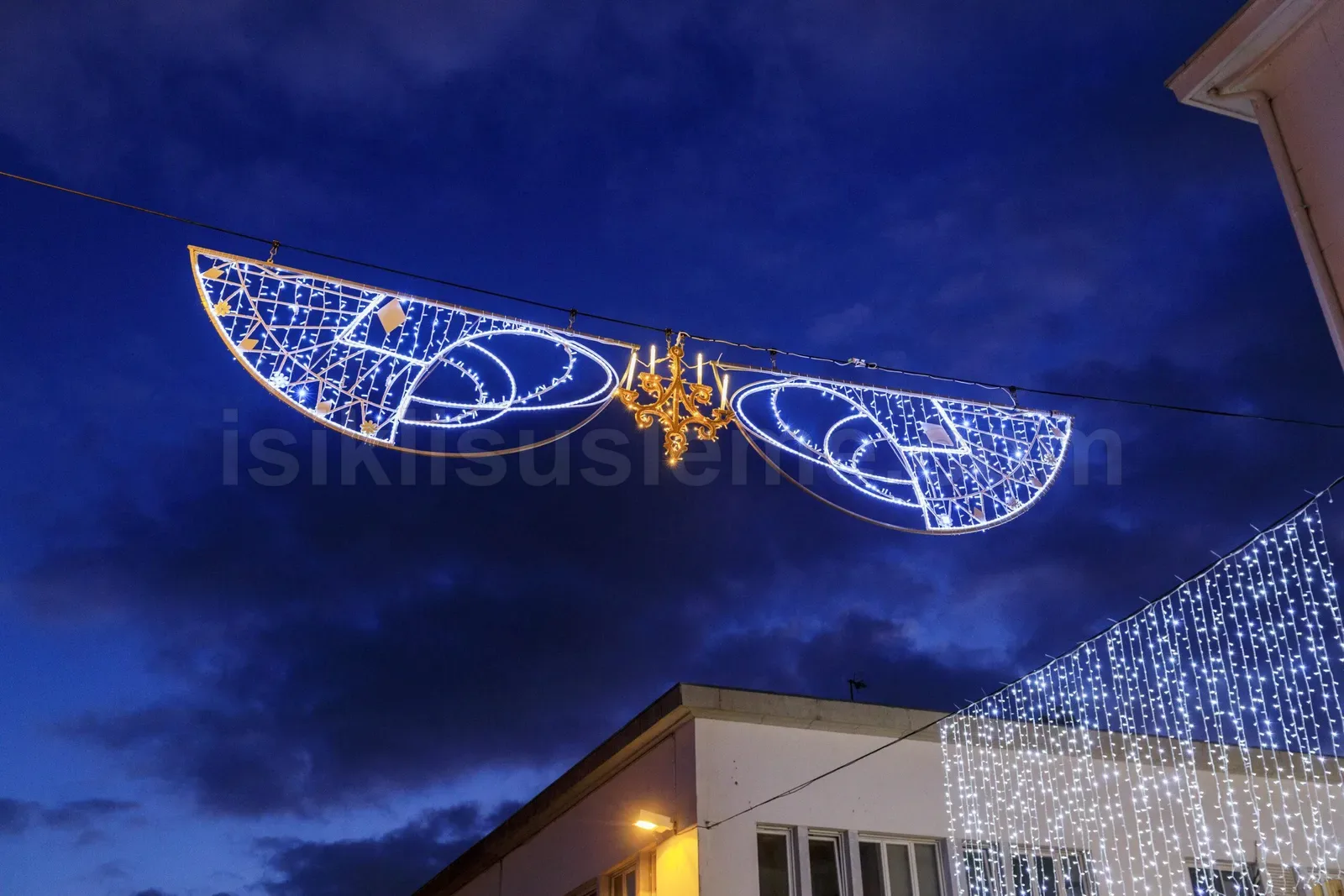 Geceleri cadde uzerine asili buyuk kanat seklinde mavi beyaz LED motif ve binada LED perde isik