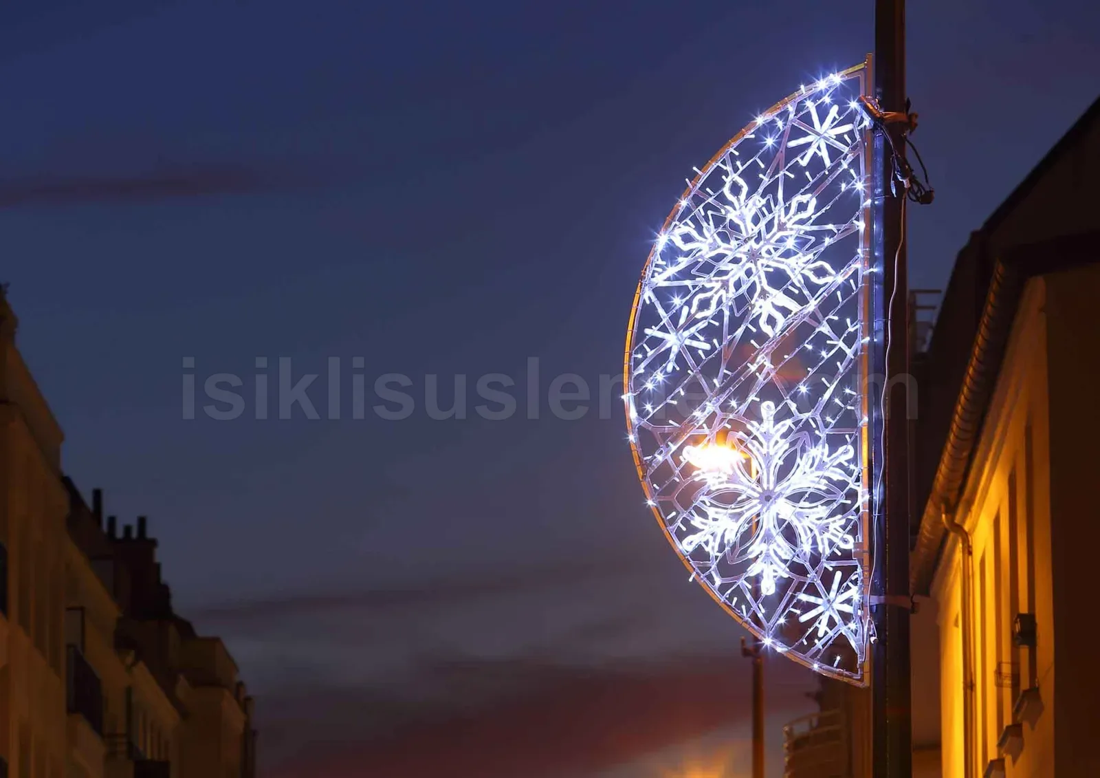 Alacakaranlikta bir elektrik diregi uzerine monte edilmis beyaz LED kar tanesi motifi