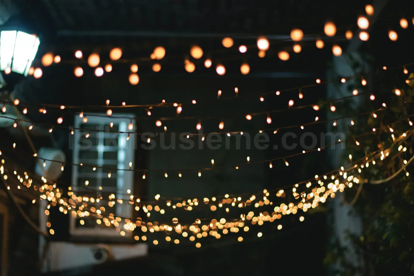 Kafe avlusunda sicak sari ip LED isiklar cerceve boyunca gece ortaminda asili duruyor