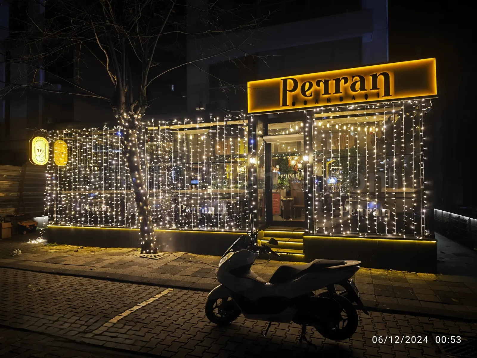 Petran adli kafenin tum cam cephesini kapatan sicak beyaz perde LED susleme gece gorunumu