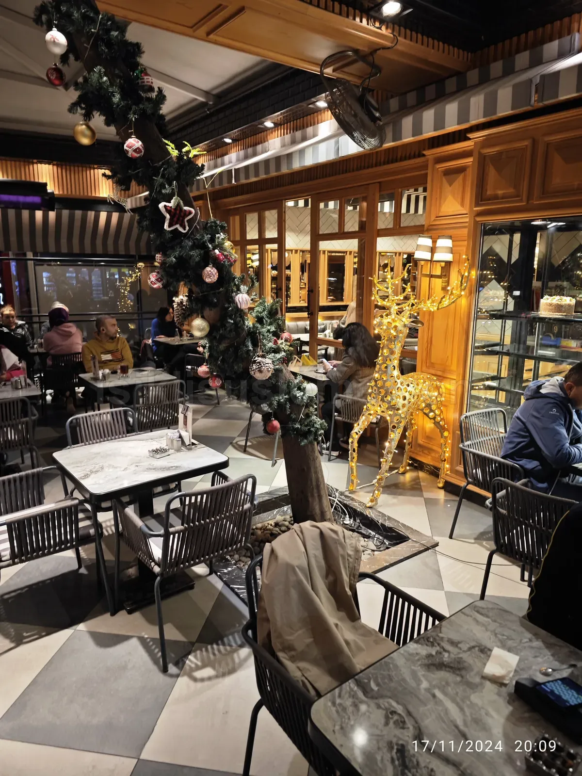Kafenin ic mekaninda altin rengi led ren geyigi figuru ve yilbasi agaci susleme duzenlemesi