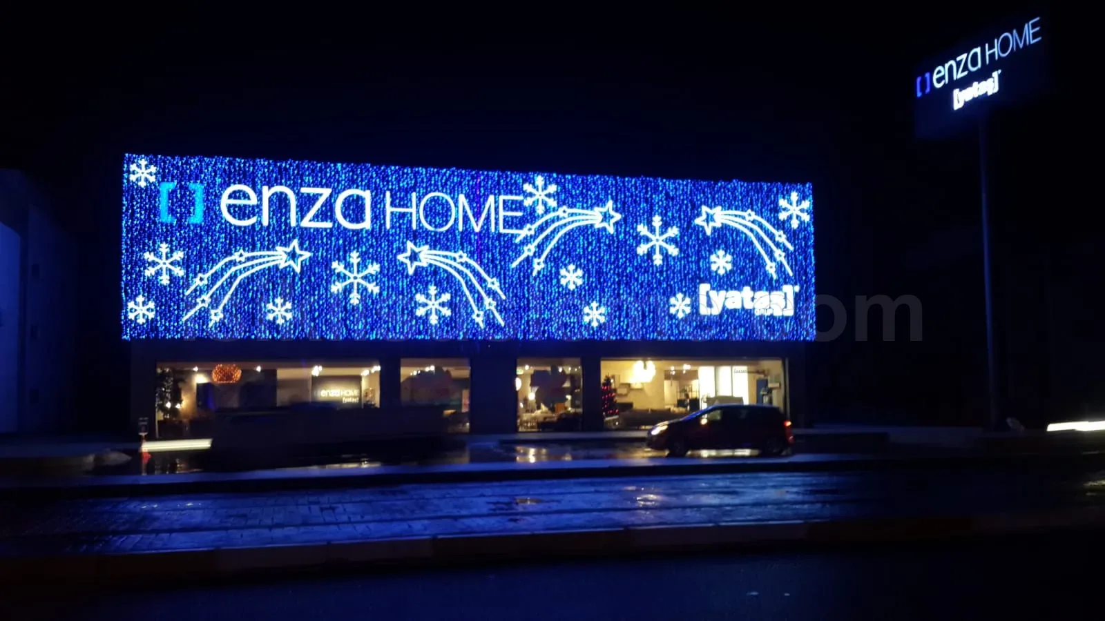 Enza Home mobilya magazasi genis cephesinde mavi LED yagmur zemin uzerine beyaz kar tanesi ve yildiz motifleri