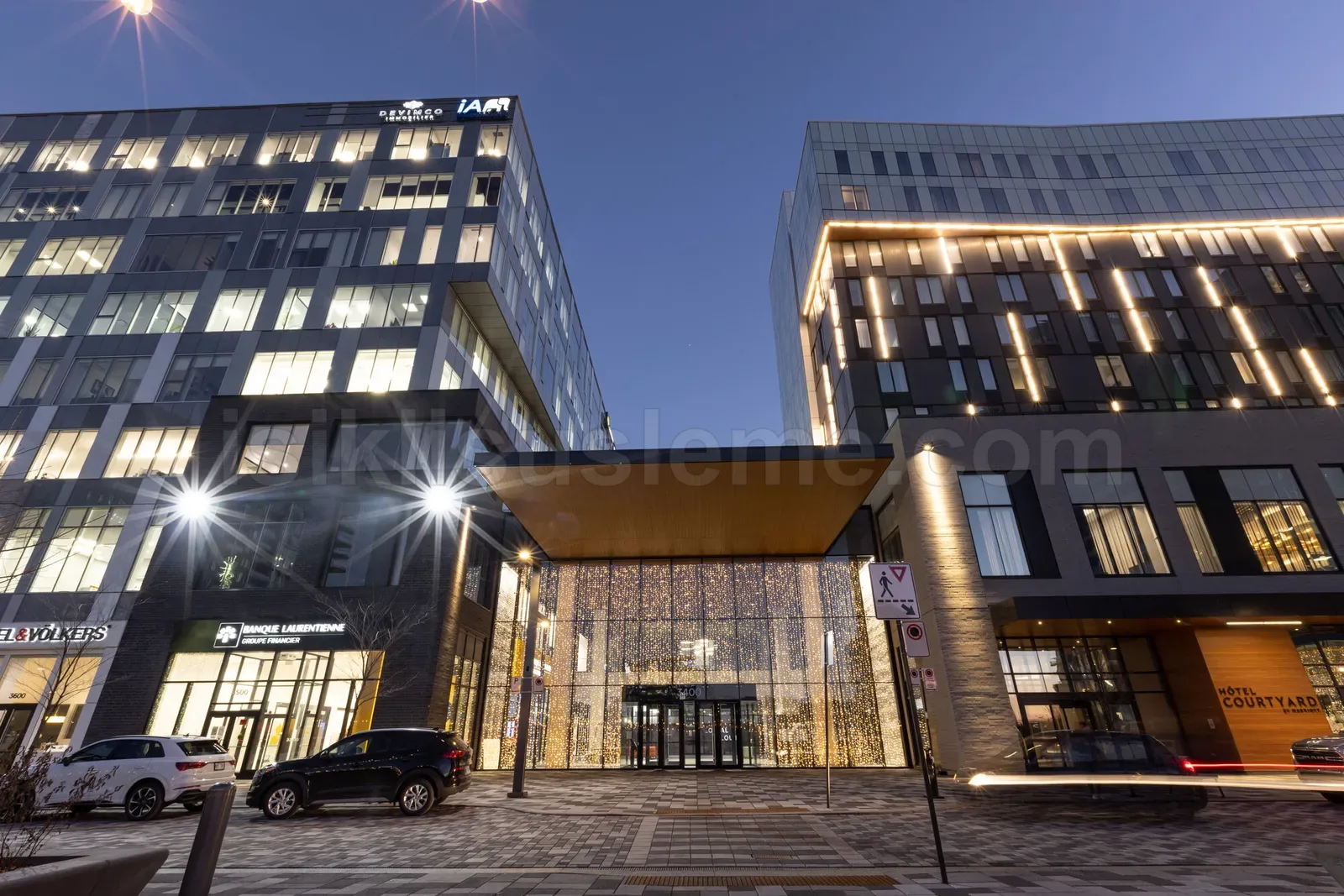 Akşam aydınlatmasında modern plaza oteli girişi ve bina kenarlarında sarı LED şerit süslemesi