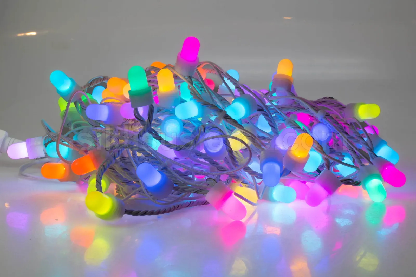 Farkli renklerde RGB top ampuller üzerinde beyaz kablolarla birbirine geçmiş LED zincir seti yüzey üzerinde