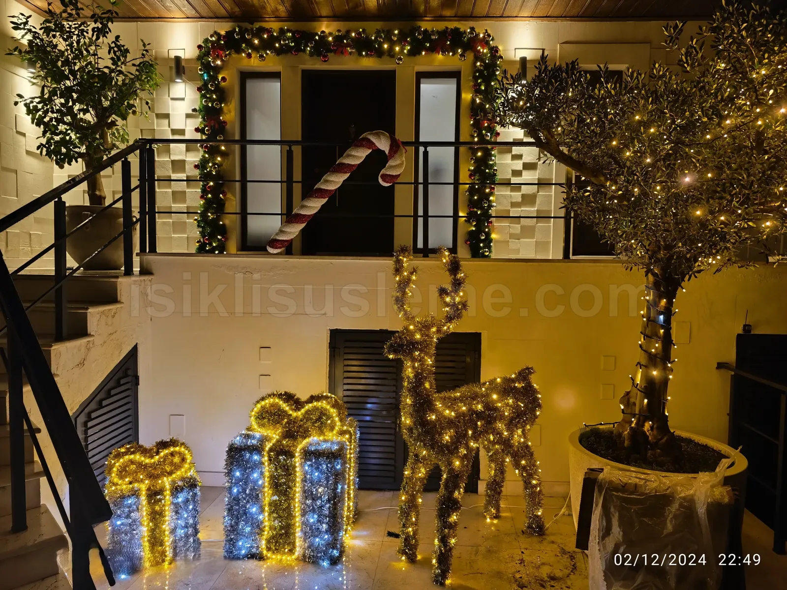 Restoran ic avlusunda led geyik figuru, isikli hediye kutusu ve seker kamisi ile garland suslenmis iki katli cephe