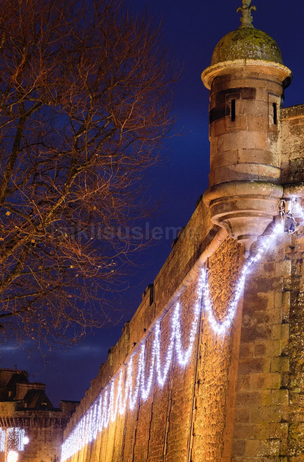 Gece mavisi gogunde tarihi tas sur duvari ve kule uzerinde soguk beyaz perde led ile yilbasi susleme
