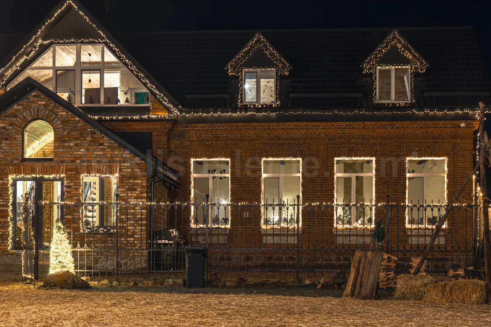 Gece tugla bina pencere cercevelerini cevreleven sicak sari LED susleme ve once kucuk cam agaci
