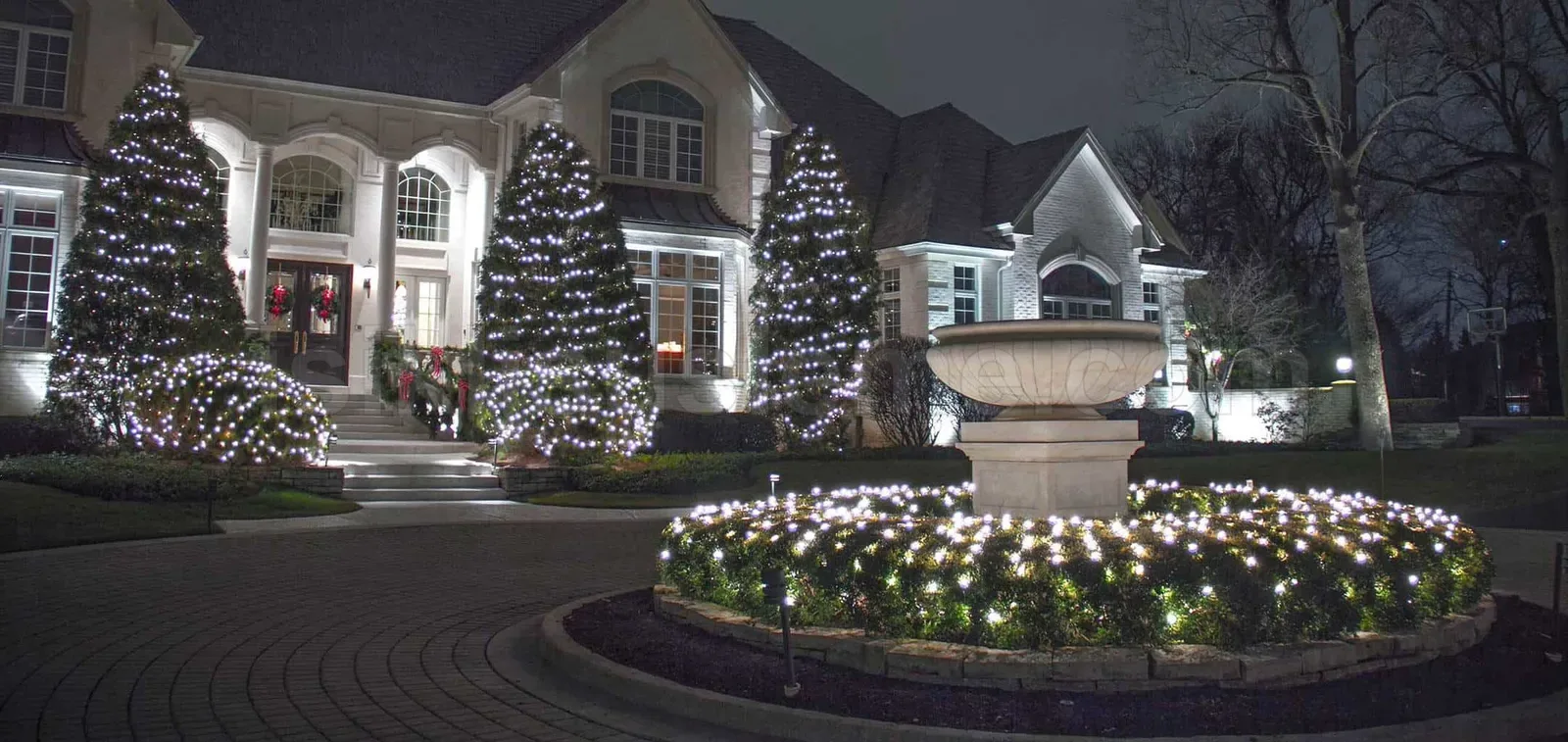 Gece bahcede beyaz LED ile isiklanan agaclar ve villa giris cephe aydinlatmasi